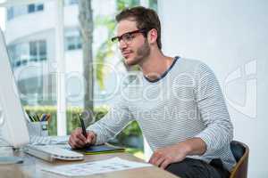 Handsome man working on computer and taking notes