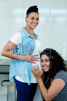 Portrait of woman listening to pregnant partners stomach