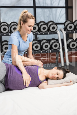 Smiling trainer massaging pregnant woman