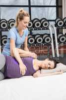 Smiling trainer massaging pregnant woman