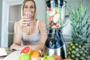 Pretty blonde woman holding her homemade smoothie
