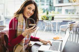 Woman using her laptop and drinking coffee