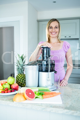 Blonde woman preparing a smoothie in the kitchen