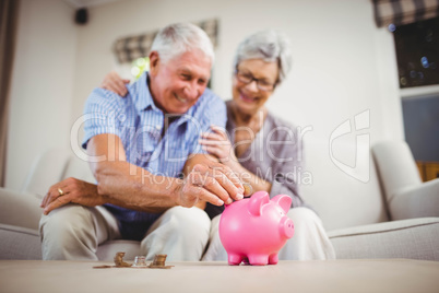 Senior man putting coins in piggy bank