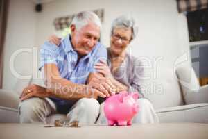 Senior man putting coins in piggy bank