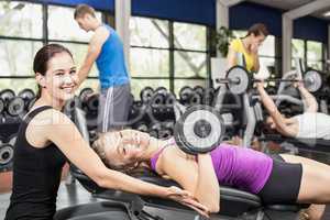 Smiling woman working out with dumbbells with female trainer