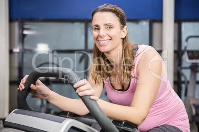 Smiling pregnant woman sitting on exercise bike