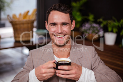 Smiling man is holding a cup of coffee