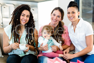 Portrait of three women sitting on sofa with a baby