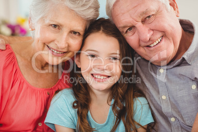 Grandparents and granddaughter sitting together on sofa