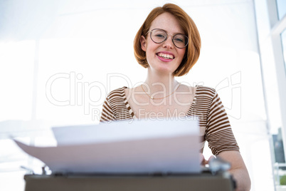 smiling hipster woman typing on her typewriter