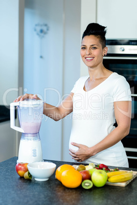 Pregnant woman preparing fruit juice in blender