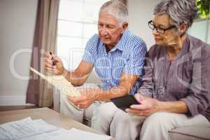 Senior couple calculating bills in living room