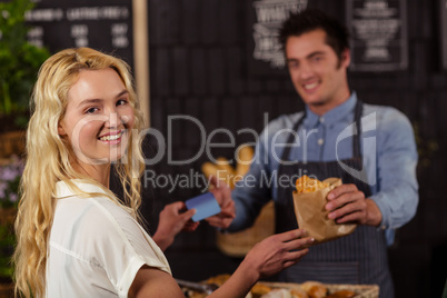 Portrait of a smiling woman paying with credit card