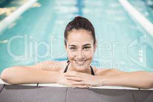 Smiling brunette leaning on poolside