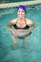 Pregnant woman standing in the pool and touching her belly