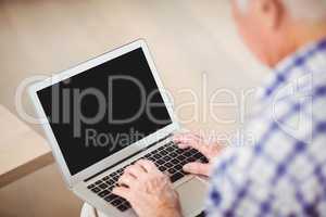 Senior man using laptop in living room