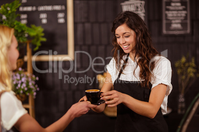 Pretty waitress offering cup of coffee to customer