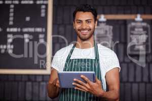 Smiling barista using tablet and looking at the camera