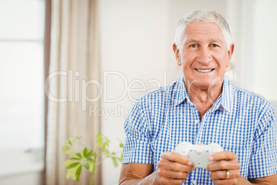 Senior man holding joystick and looking at camera