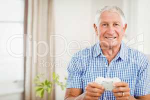Senior man holding joystick and looking at camera