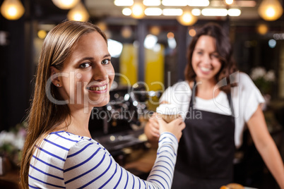 Smiling woman keeping disposable cup from barista