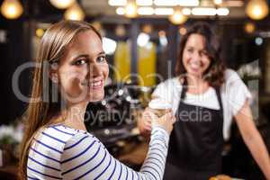 Smiling woman keeping disposable cup from barista