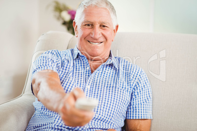 Senior man sitting and watching television at home