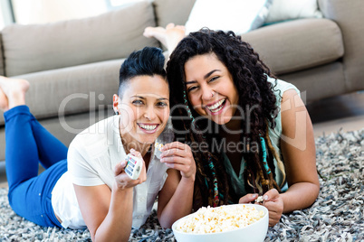 Lesbian couple lying on rug and watching television