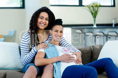 Pregnant lesbian couple with a pair of pink baby shoes