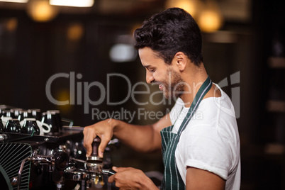 Smiling barista preparing coffee with a machine