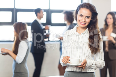 Businesswoman smiling at camera while her colleagues standing in