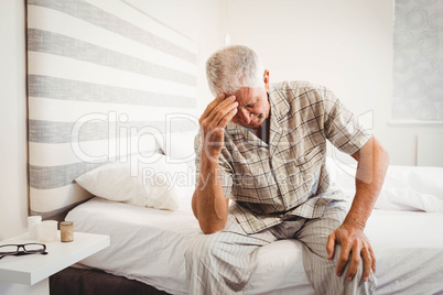 Frustrated senior man sitting on bed