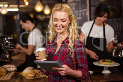Smiling blonde customer in front of the counter using tablet