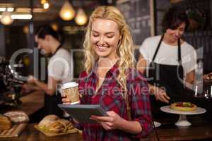 Smiling blonde customer in front of the counter using tablet