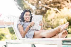 Young woman reading magazine near poolside