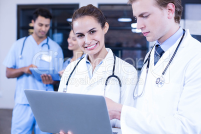 Doctors using laptop and smiling at camera