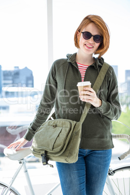 Cute hipster with her bike and disposable cup