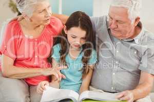 Grandparents reading a book with granddaughter
