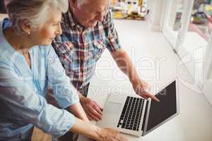 Senior couple discussing while using laptop