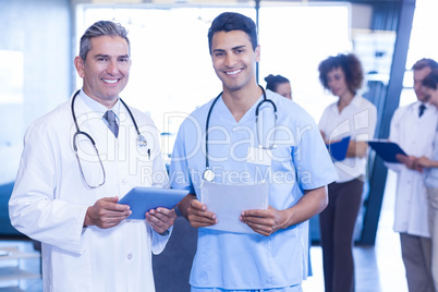 Doctors with digital tablet and medical report looking at camera