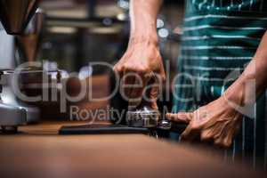 Waiter squeezing the coffee in the percolator