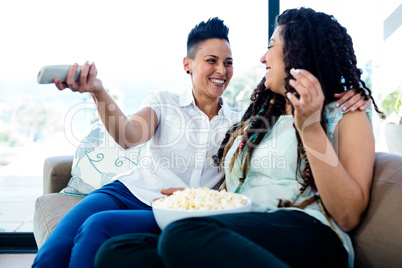 Lesbian couple watching television with a bowl of popcorn