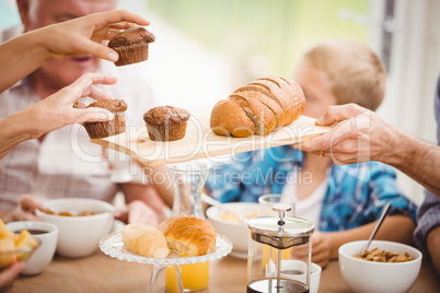 Close-up of hands passing cupcake and bread