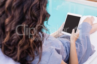 Young woman using digital tablet near poolside