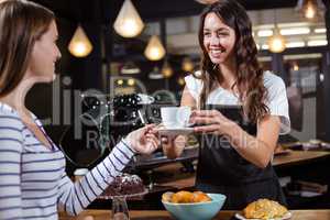 Smiling barista giving white cup to woman