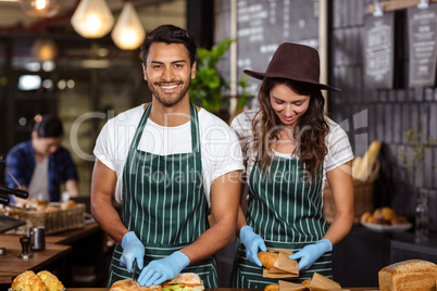 Smiling baristas preparing sandwiches