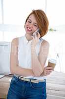 smiling hipster business woman sitting on her desk on the phone