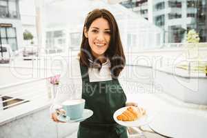 Waitress posing with coffee and croissant