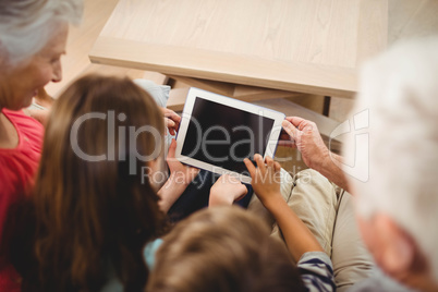 Children using tablet with their grandparents